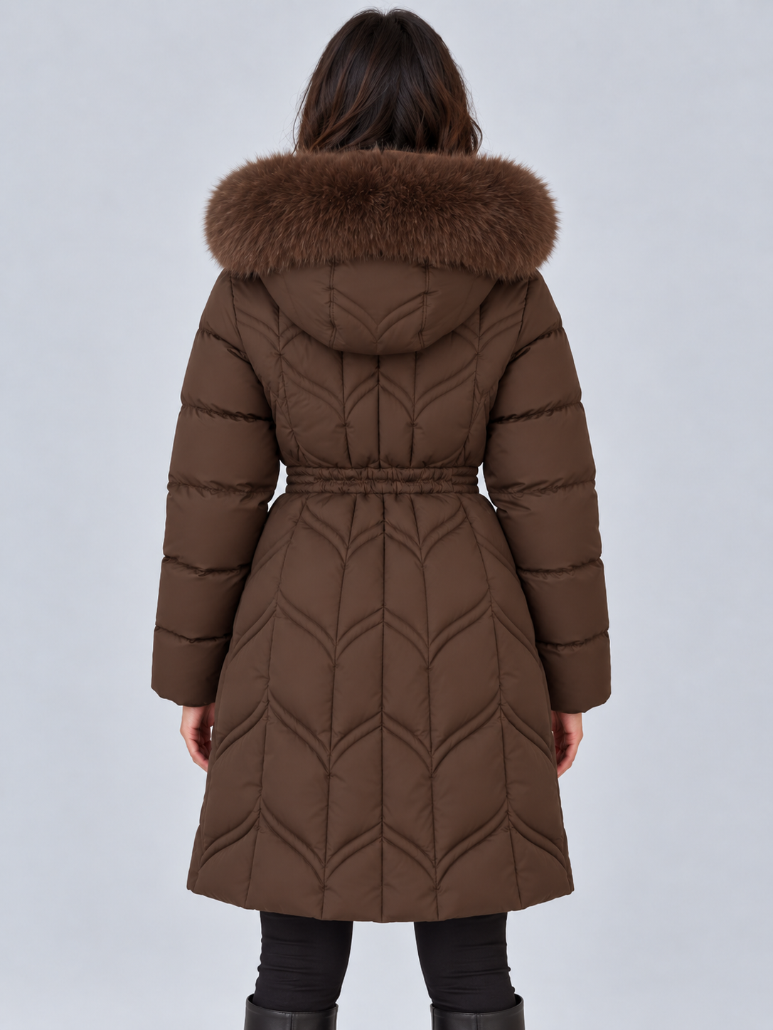 Back view of the brown puffer coat displaying the wide faux fur-trimmed hood, defined waist, long sleeves, and curved quilted panels.