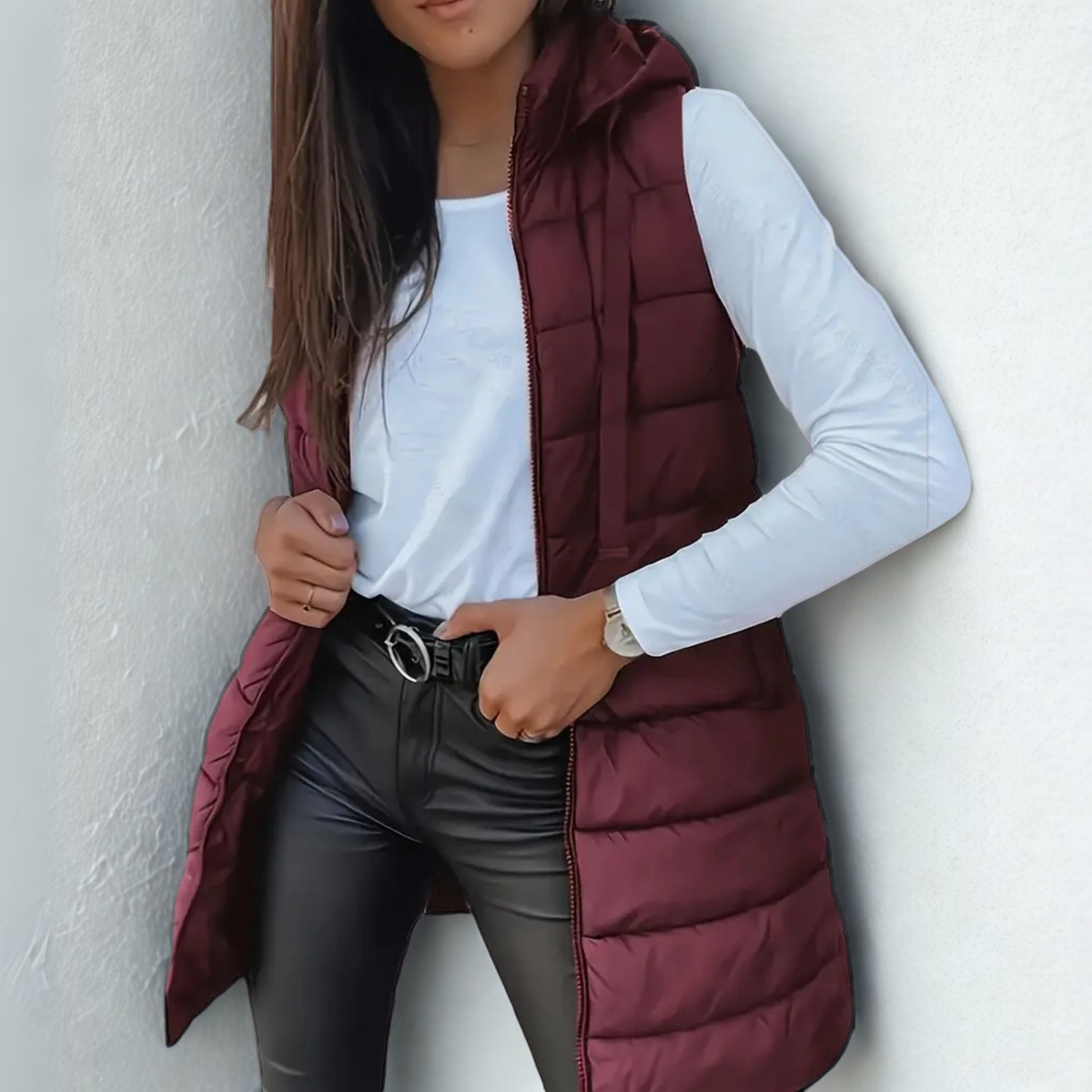 Deep burgundy long hooded puffer vest worn open over a white shirt, showing its extended coverage and horizontal padded panels.