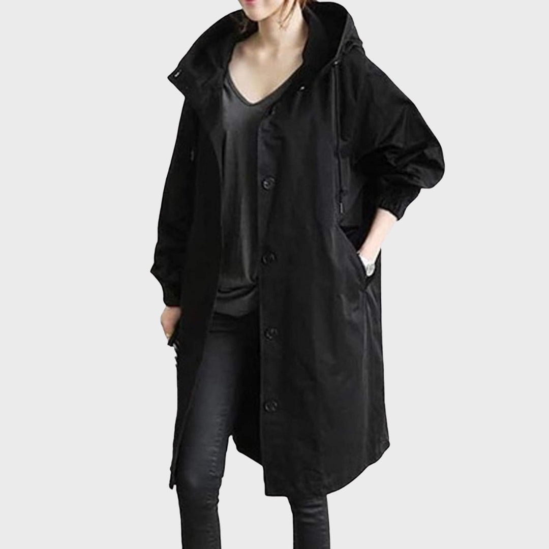 Front view of a long black hooded rain coat with a button fastening, side pockets, and gathered cuffs.