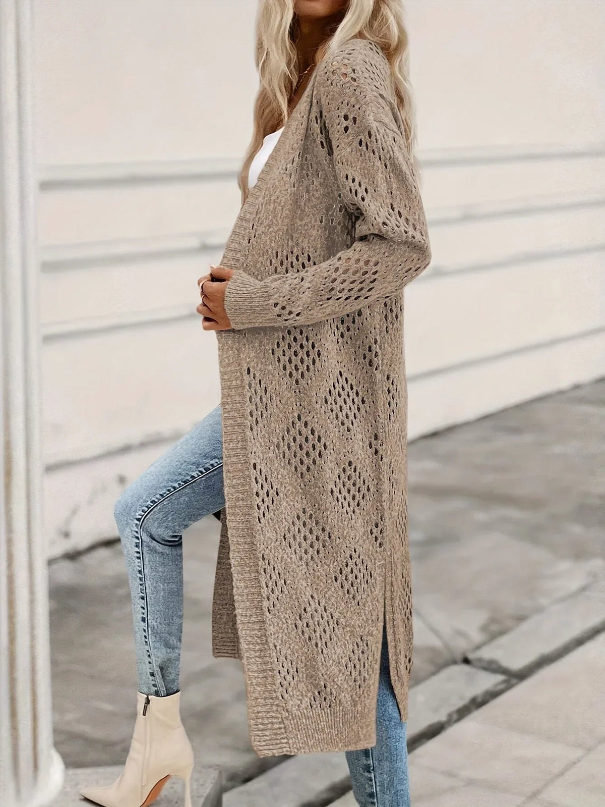 Side view of the calf-length open-front cardigan showing its flowing silhouette, long sleeve, diamond openwork, and high side slit.