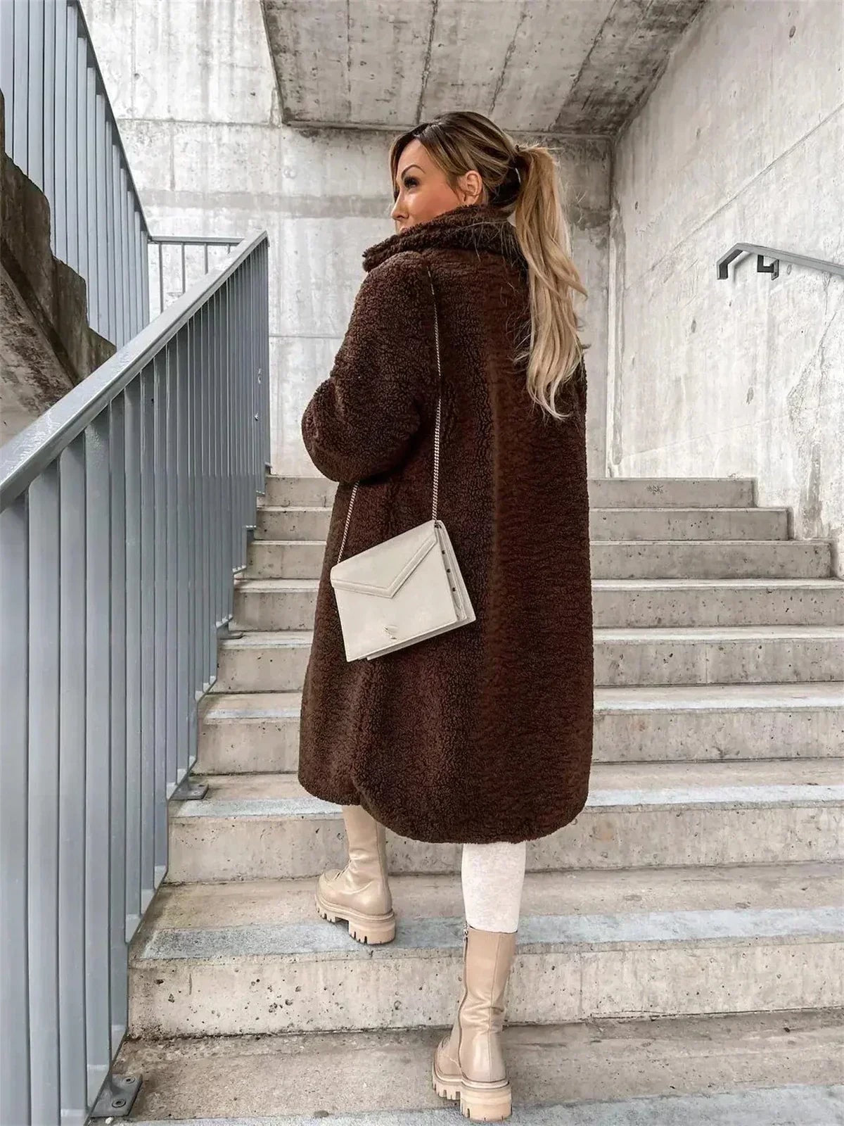 Rear three-quarter view of the dark brown teddy coat, showing the long rounded hem and plush back texture.