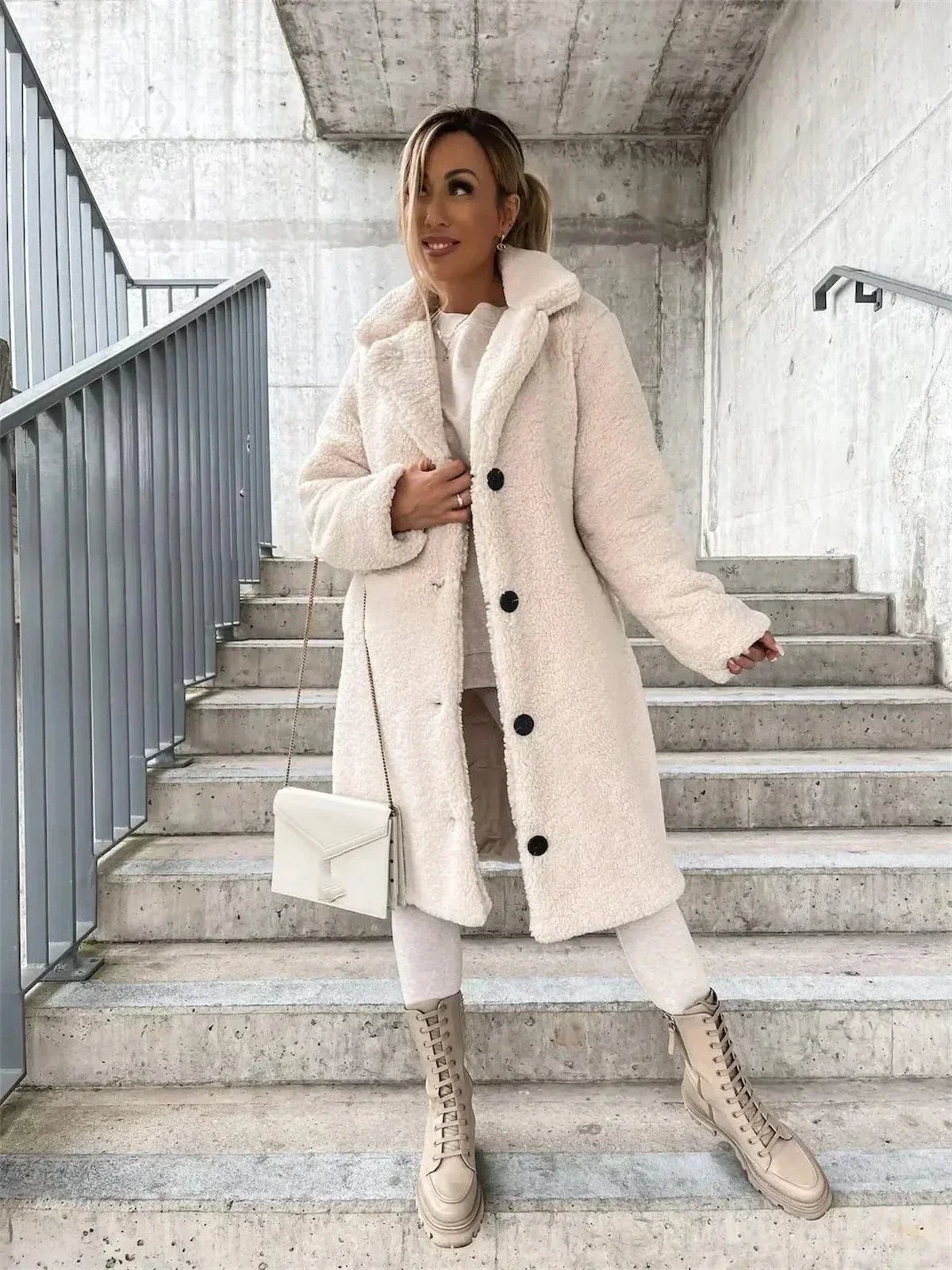 Full front view of the cream long teddy coat worn closed, showing its extended coverage, notched collar, button fastening, and relaxed sleeves.