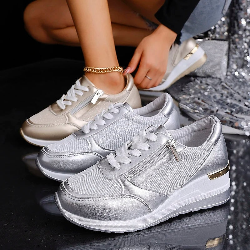 Silver and champagne metallic platform sneakers arranged together, showcasing their lace-up fronts, side zips, and contrasting heel accents.