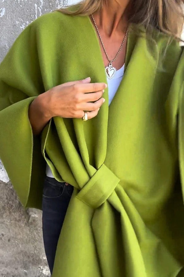Olive green cape jacket in close view, highlighting the overlapping front panels and gathered waist detail.