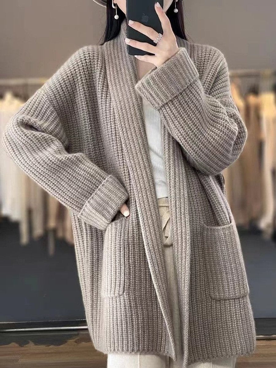 Model wearing the cardigan in a taupe-gray shade, highlighting the open front, long sleeves, wide cuffs, and patch pockets.