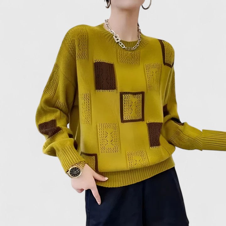 Mustard crew neck sweater featuring brown contrasting patchwork, decorative openwork panels, and a ribbed hem and cuffs.