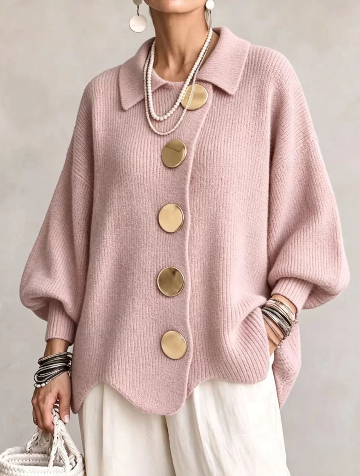 Soft pink oversized button-front cardigan showing its rounded buttons, generous sleeves, and gently curved lower edge.