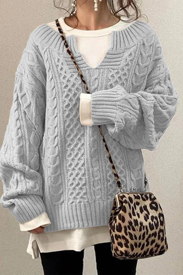 Light gray oversized cable knit sweater with a deep V-neckline, long sleeves, and contrasting white layered top.