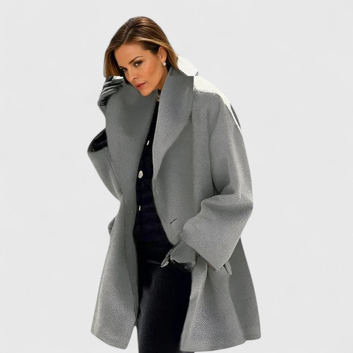 Gray oversized coat with a prominent lapel collar and roomy sleeves, styled open over dark clothing.