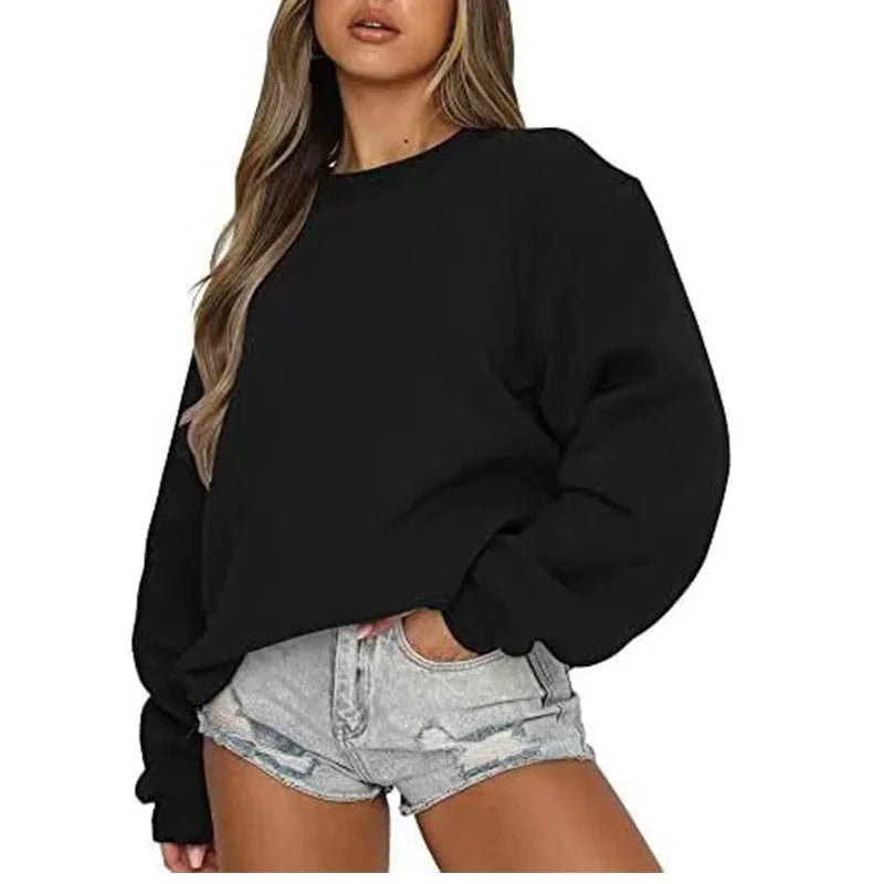 Model wearing a black oversized crew neck sweatshirt with dropped shoulders, long sleeves, and ribbed cuffs, paired with denim shorts.