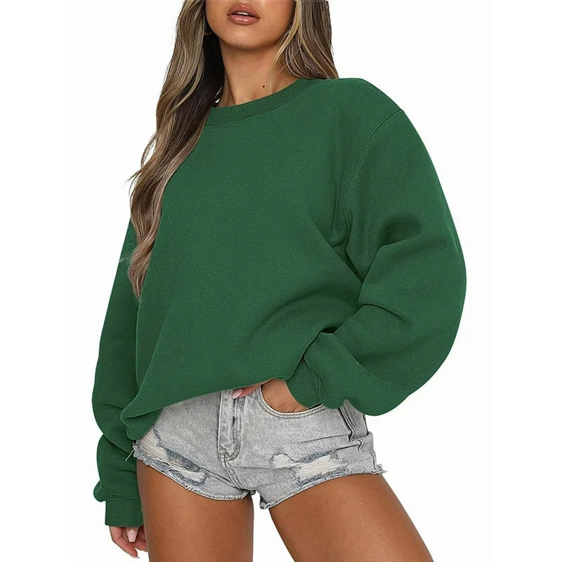 Deep green oversized sweatshirt paired with light denim shorts, showing the roomy sleeve shape and ribbed cuff.
