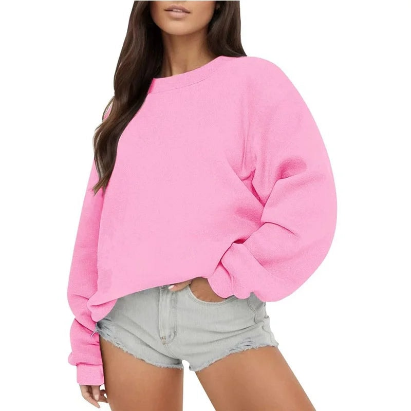 Bright pink oversized sweatshirt with a clean crew neckline and long sleeves, worn with light denim shorts.