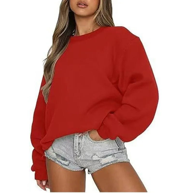 Red oversized sweatshirt styled with light denim shorts, showing its simple crew neck and roomy long sleeves.