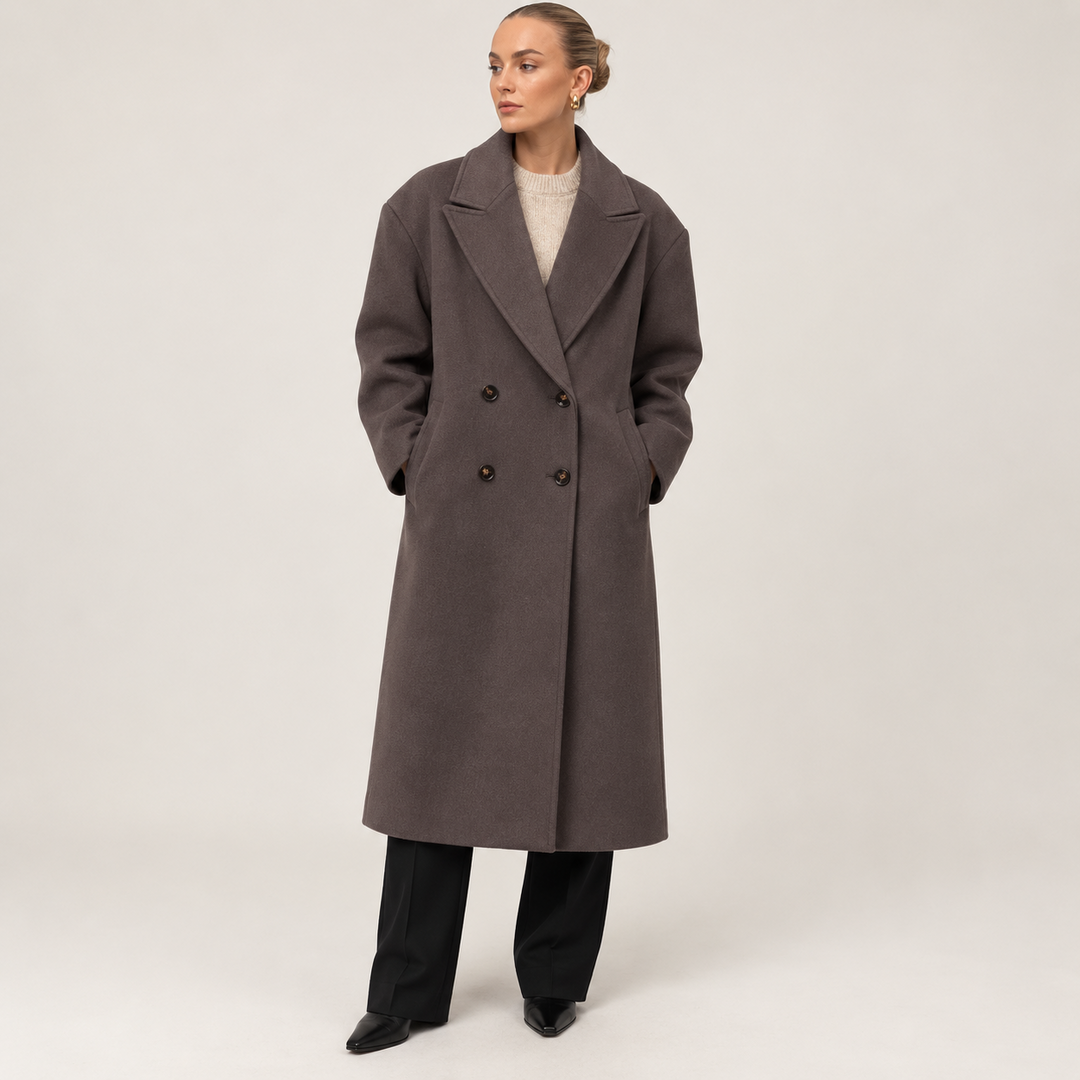 Three-quarter front view of the long taupe coat with its structured lapel collar, four-button front, and hands placed in the side pockets.
