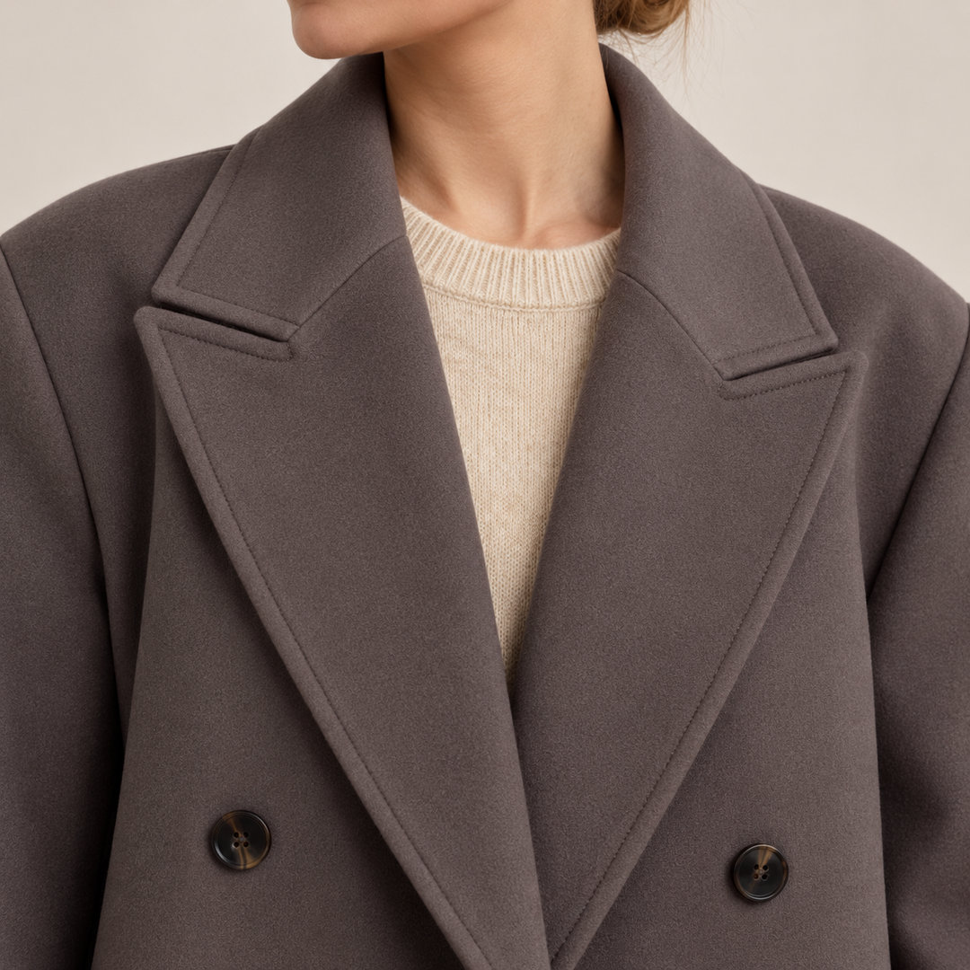 Close-up of the coat’s wide notched lapels and two dark buttons over a light knit sweater.