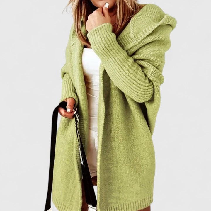 Light green open-front cardigan worn over a white top, with the hood resting at the shoulders and ribbed cuffs framing the long sleeves.