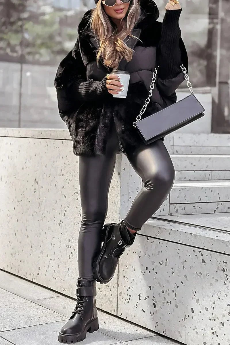 Black mixed-texture hooded puffer jacket worn with the hood raised, showing its long sleeves, ribbed cuffs and plush front sections.