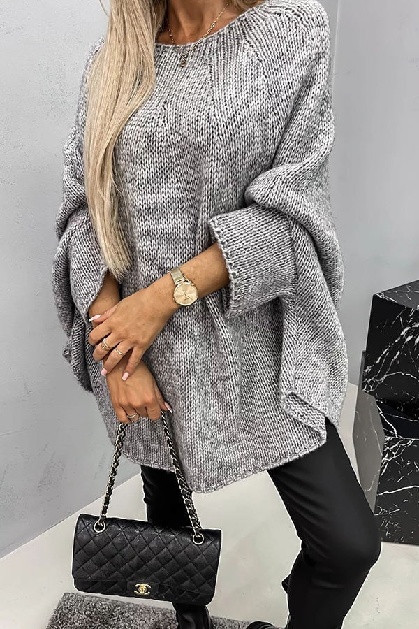 Gray oversized knit poncho sweater showing its loose draped fit, wide sleeves, crew neckline, and textured knit surface.