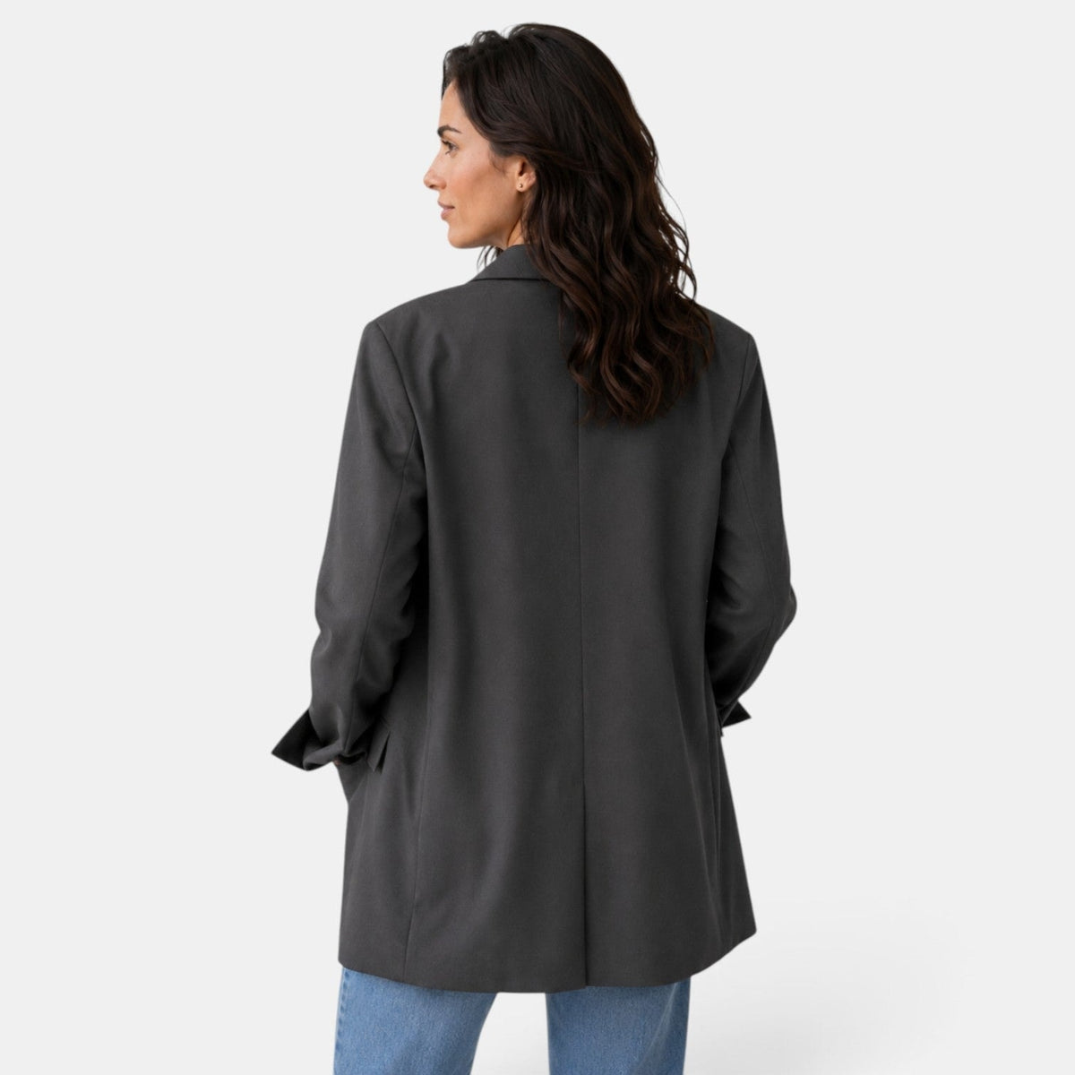 Back view of the charcoal oversized blazer showing the straight center seam, relaxed drape, long sleeves, and split cuffs.
