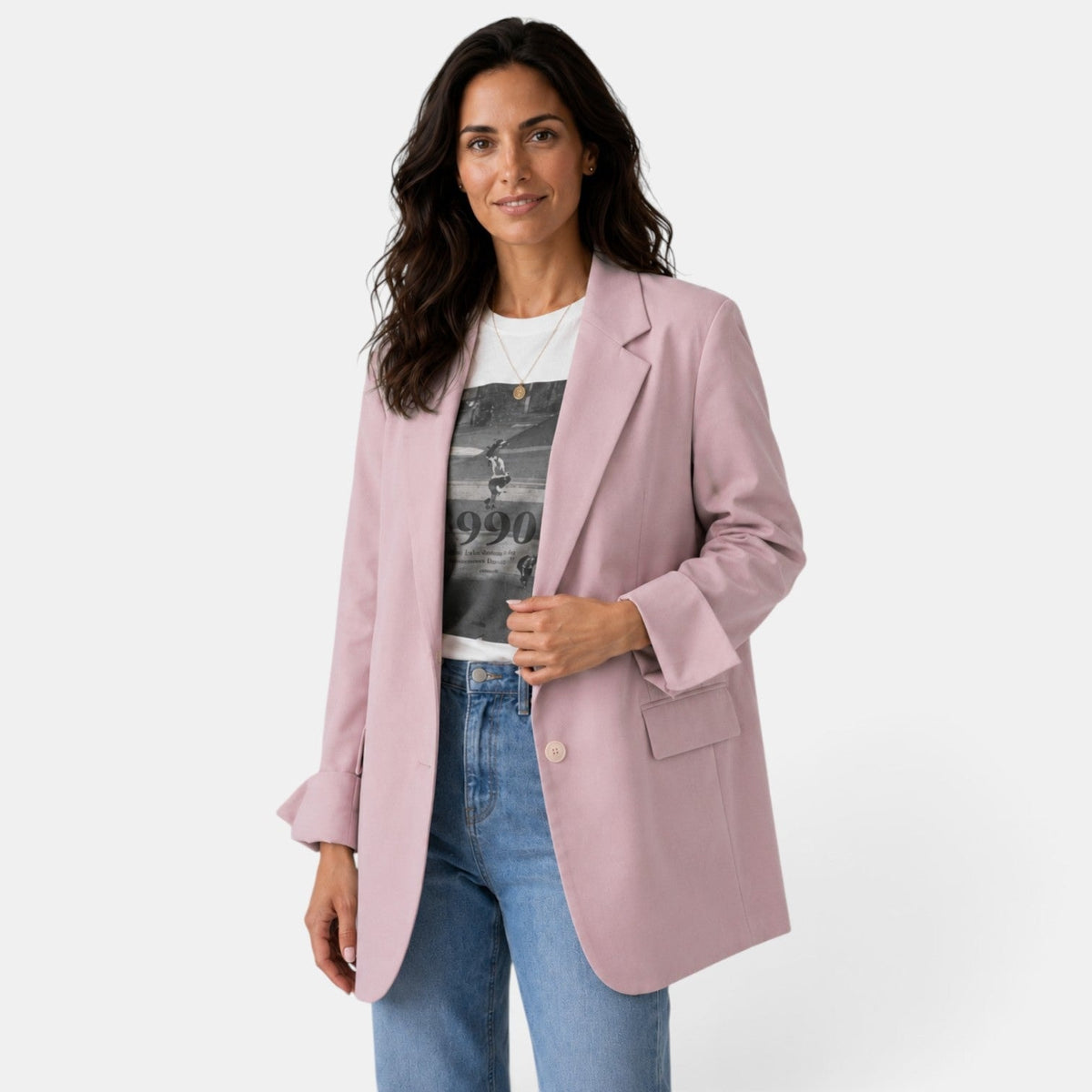 Front view of a blush pink oversized two-button blazer styled open with a graphic T-shirt and jeans, featuring notched lapels and flap pockets.