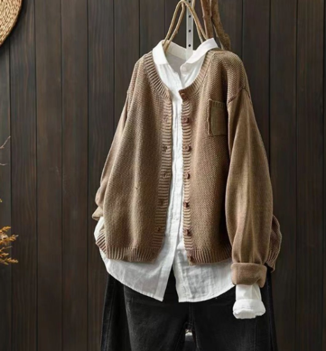 Taupe oversized cardigan layered over a white shirt, featuring a full button front, long sleeves, ribbed edging, and a chest pocket.