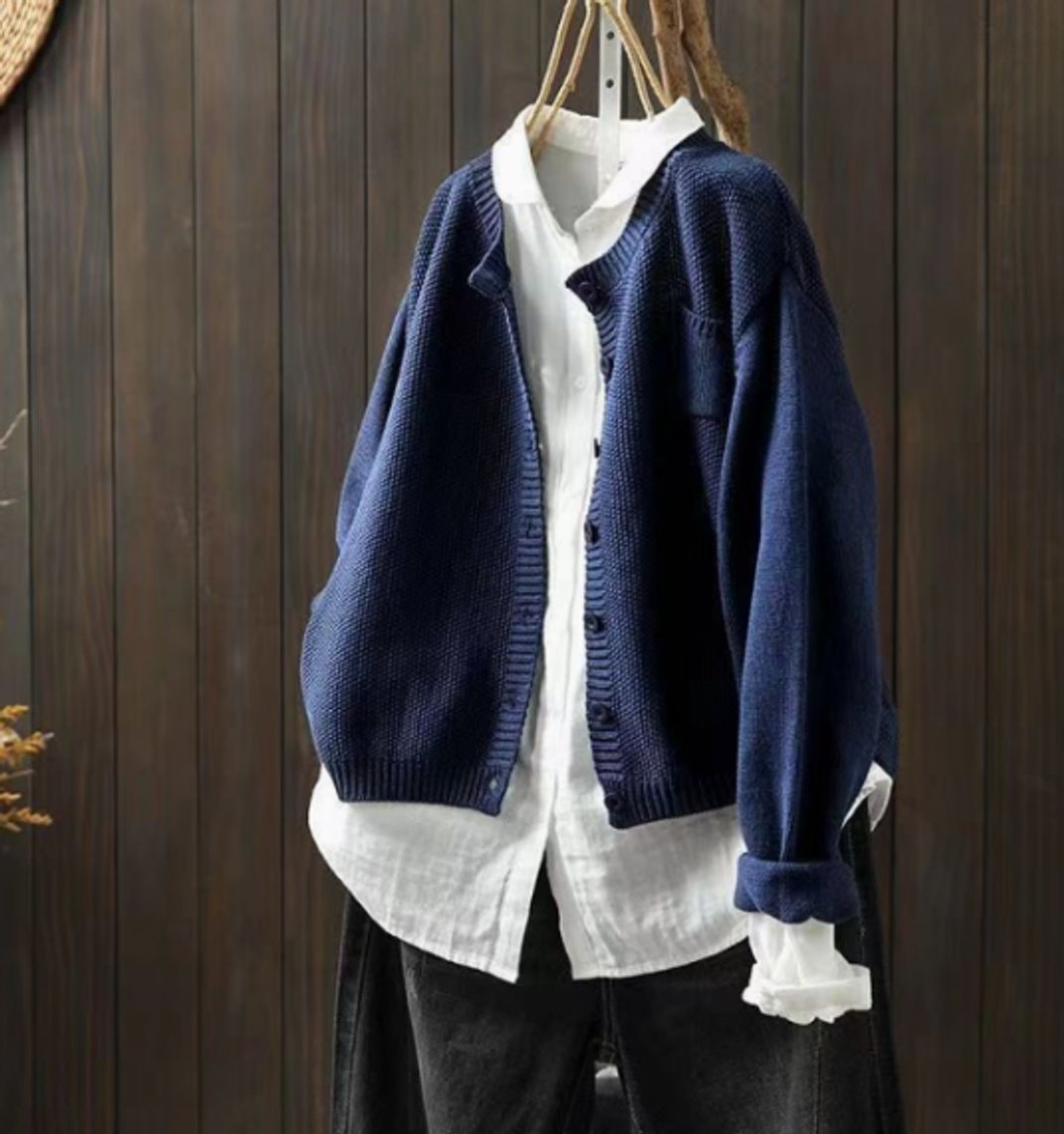 Navy oversized cardigan styled open over a white shirt, showing its relaxed shape, long sleeves, button placket, and ribbed hem.