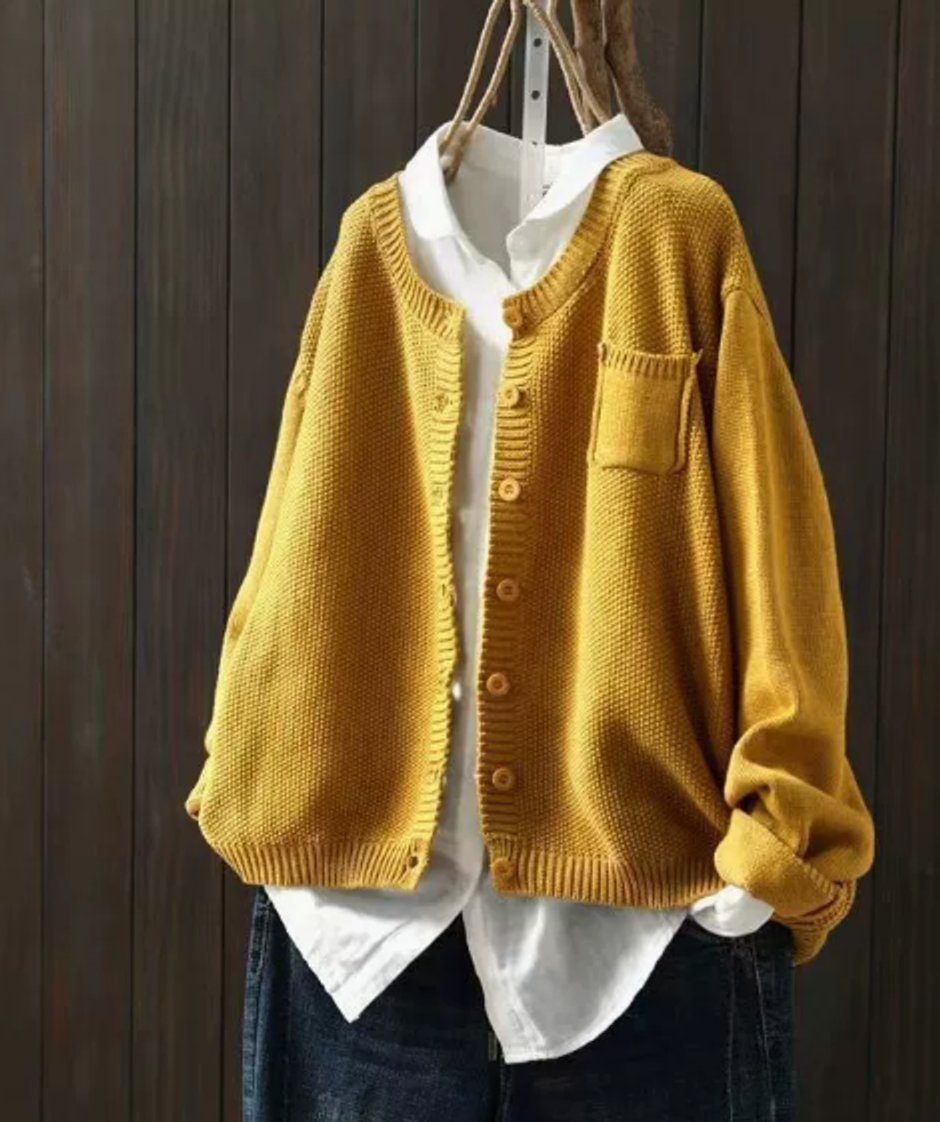 Mustard yellow oversized button cardigan layered over a white shirt, with a prominent patch chest pocket and ribbed neckline, cuffs, and hem.