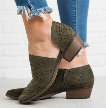 Olive perforated ankle boots with open side cutouts, visible side zipper, rounded toes, and low block heels, paired with cropped jeans.