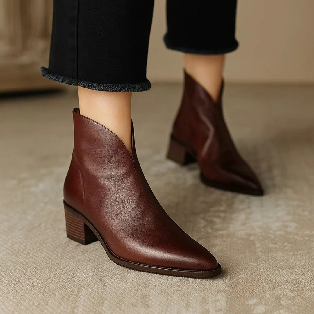 Brown pointed-toe ankle boots shown from the side with angled openings and stacked low block heels.