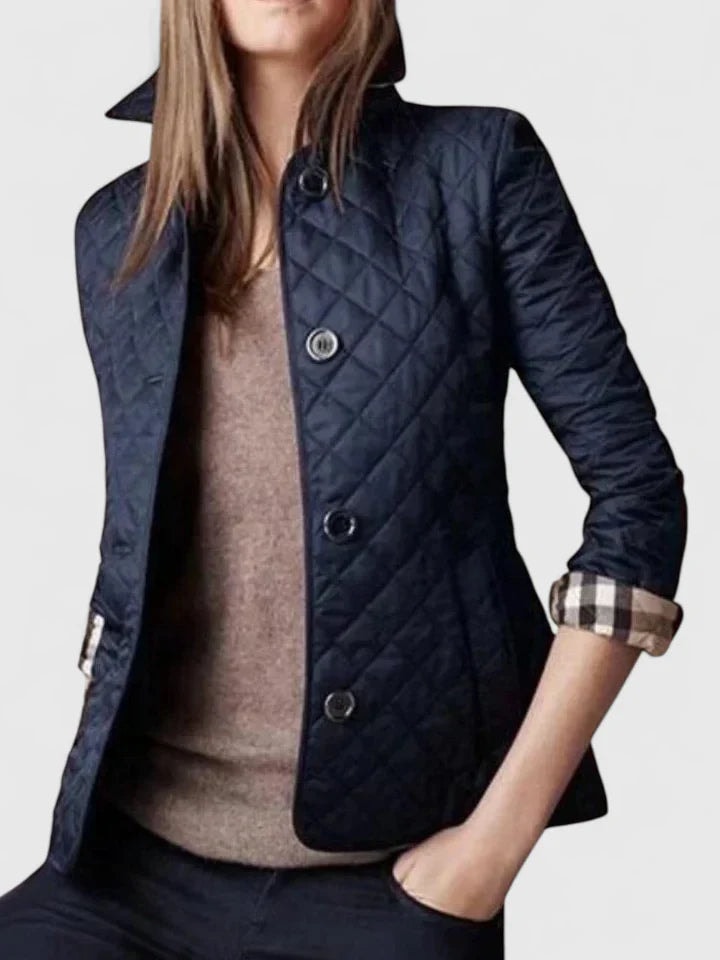 Navy quilted button-front jacket layered over a brown top, with rolled sleeves revealing contrasting checked cuffs.