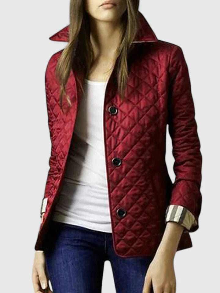 Red quilted jacket with a raised pointed collar, dark button closure, long sleeves, and a hip-length silhouette.