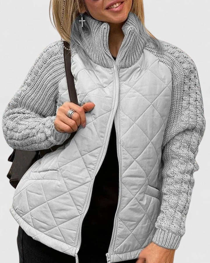 Light gray quilted jacket with textured long sleeves and high collar shown open over a dark outfit.