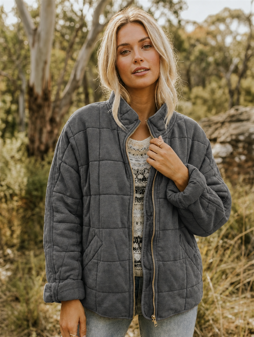 Front view of a charcoal quilted stand-collar jacket with a front zip, geometric stitching, and two patch pockets.