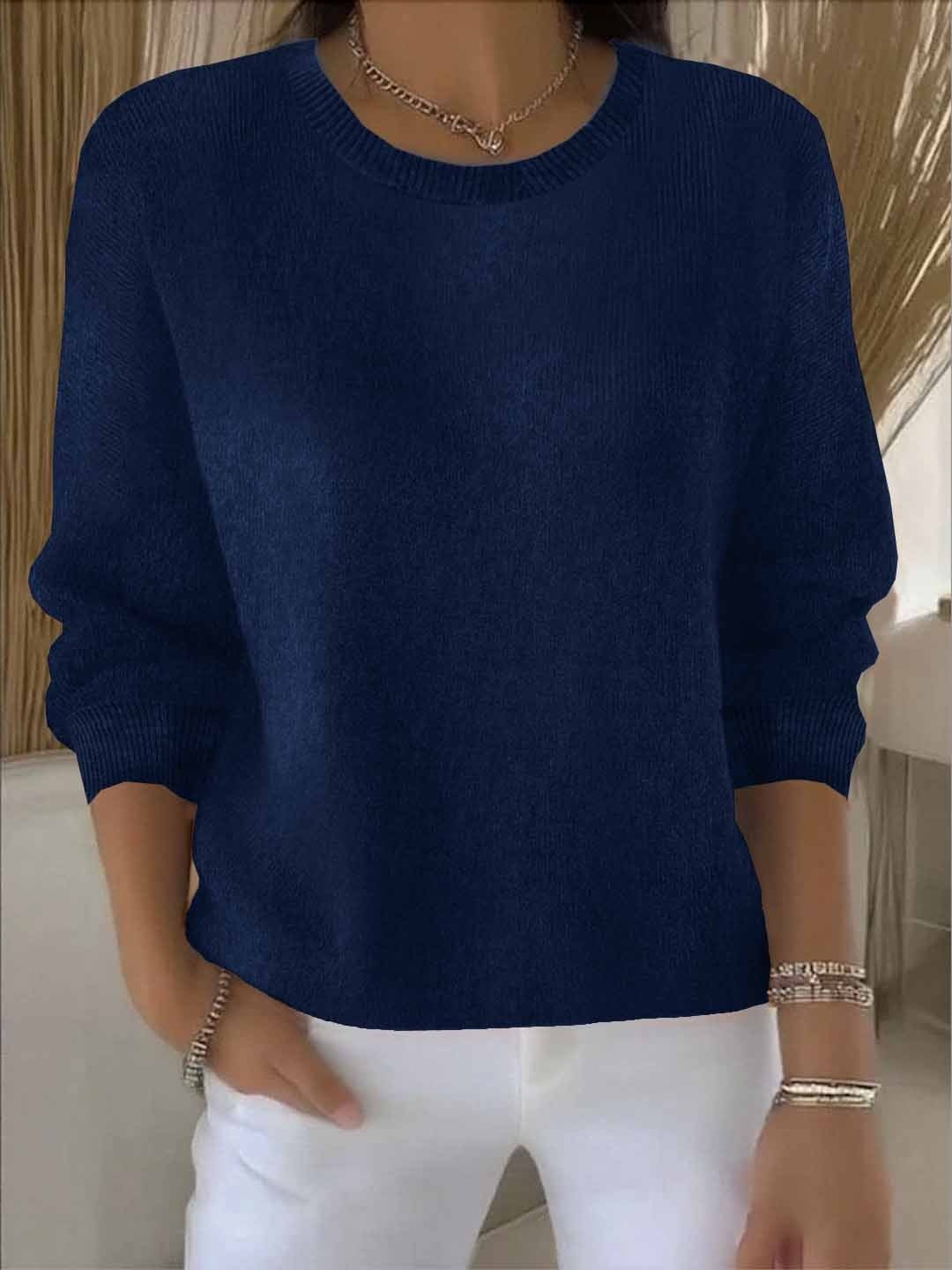 Deep navy relaxed crew neck sweater styled over white pants, with long sleeves and ribbed cuffs.