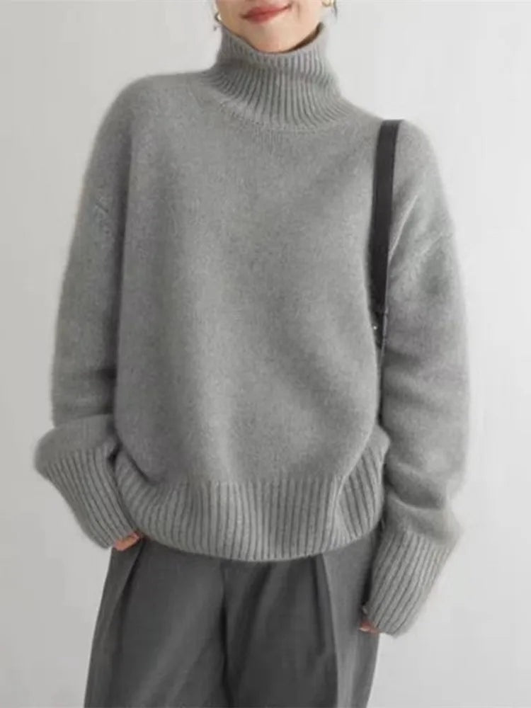 Gray turtleneck sweater shown straight on with a smooth relaxed silhouette, elongated ribbed cuffs and structured ribbed hem.