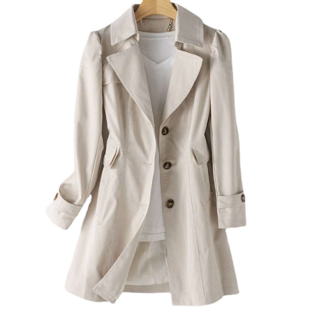 Front view of a light beige mid-length trench coat on a hanger, showing its open notched lapels, button closure, flap side pockets, and cuff straps.
