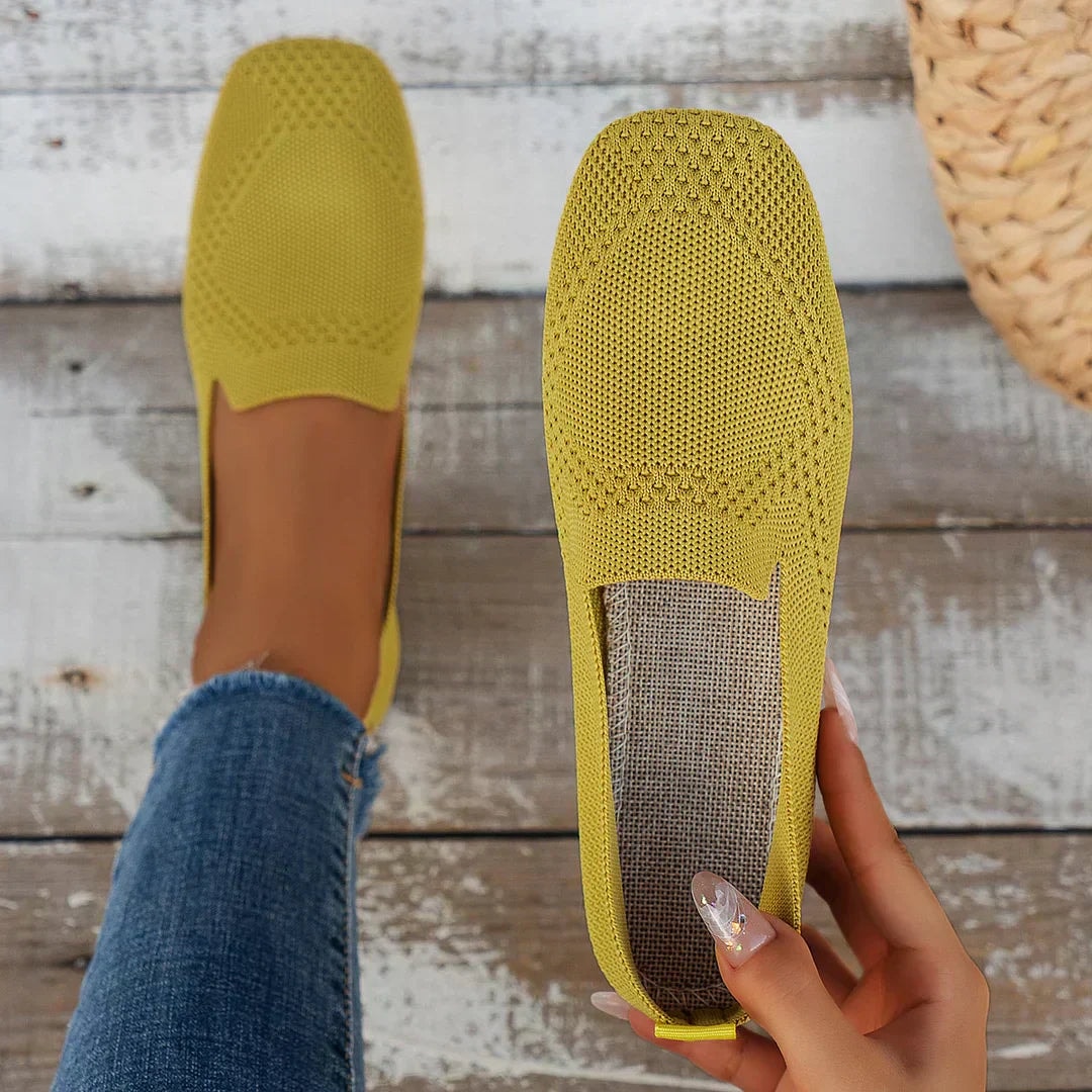 Mustard yellow flat shown both worn and from above, revealing the square toe, open-knit upper, and flat sole.