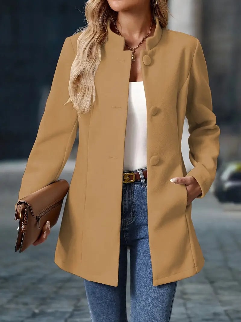 Tan coat worn open from the front with side pockets, long sleeves, and a thigh-length silhouette.
