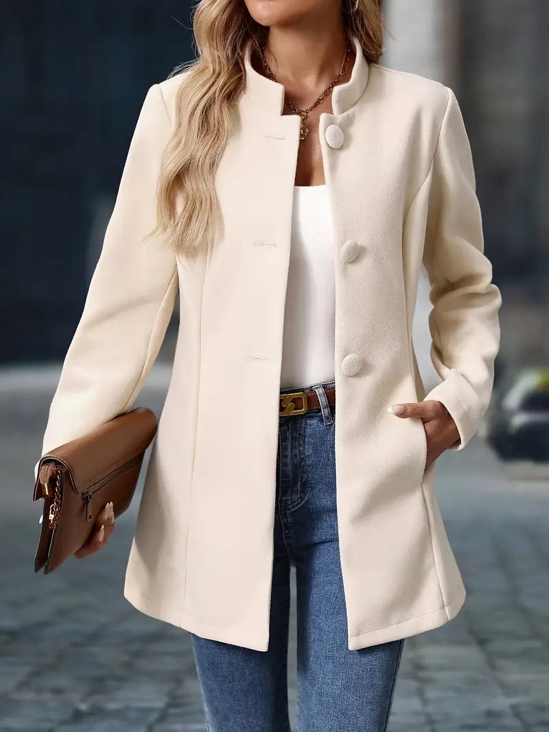 Front view of the ivory coat worn open with hands in the side pockets and a structured silhouette.