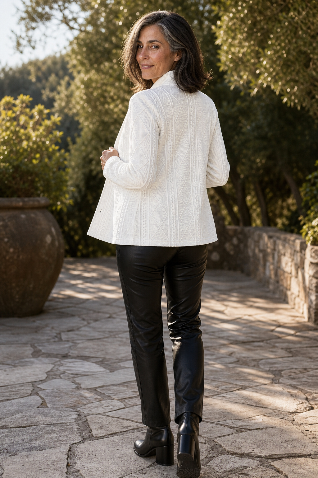Back view of the white textured blazer showing its geometric pattern, long sleeves, and hip-length cut.