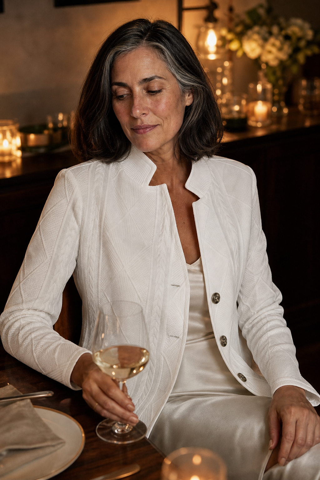 White textured blazer styled for an evening setting with a stand collar and partially fastened button front.