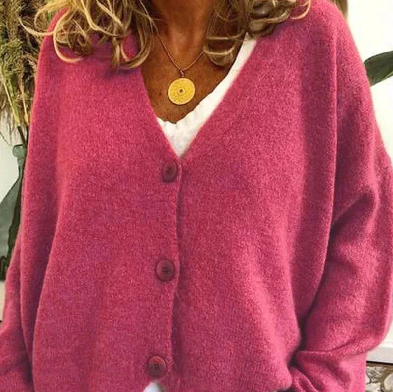 Pink button-front cardigan with a V-neck and long sleeves, shown layered over a white top.