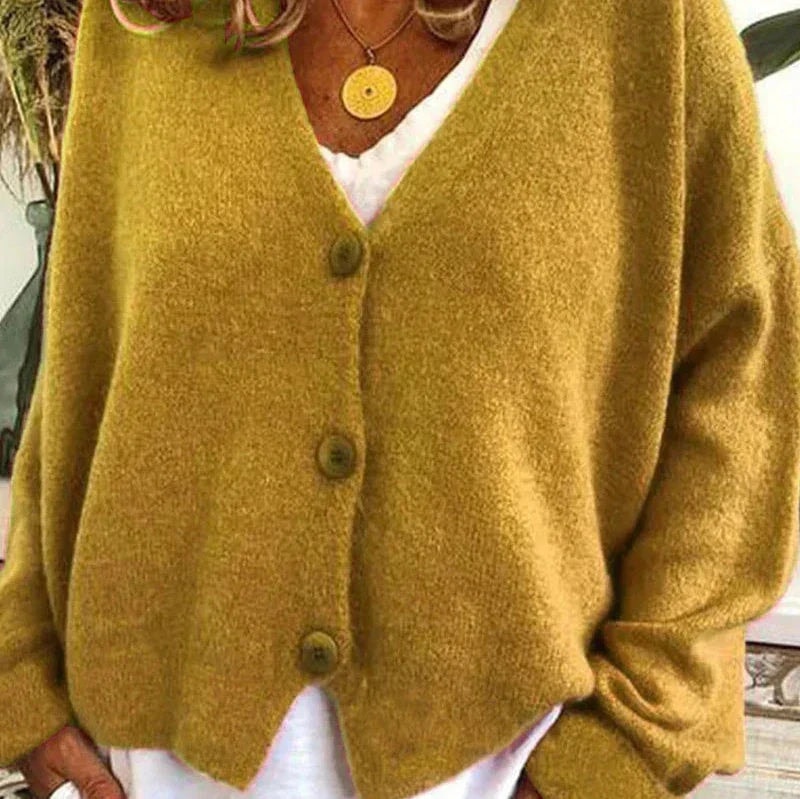 Mustard yellow V-neck cardigan with a button-front closure and relaxed long sleeves over a white top.