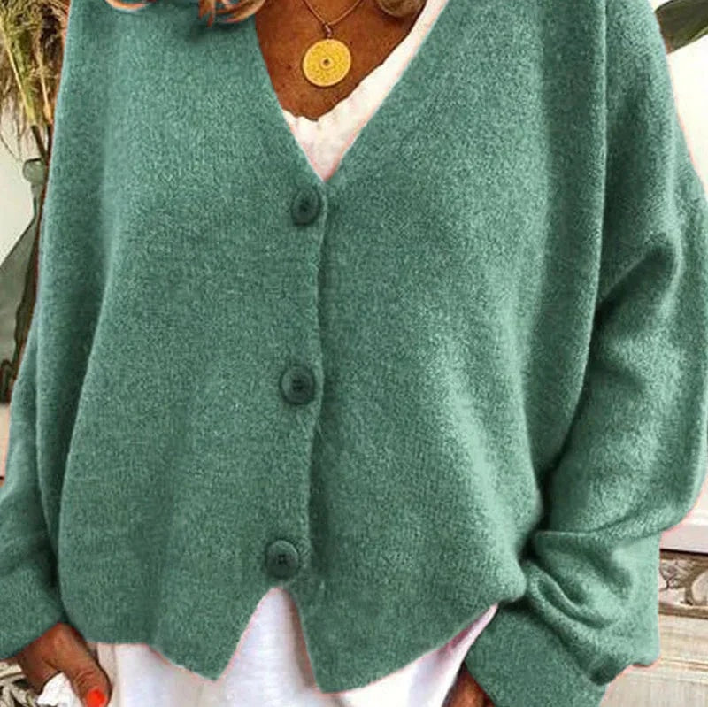 Teal green cardigan with a V-neck and three visible front buttons, worn over a white top.