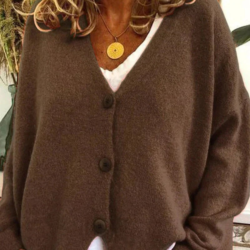 Dark brown V-neck cardigan worn open at the neckline area over a white top, with visible front buttons.
