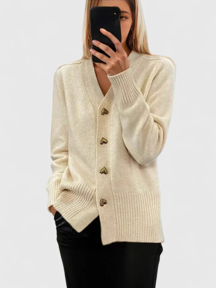 Cream V-neck cardigan with heart-shaped buttons and ribbed cuffs and hem, styled with black trousers.