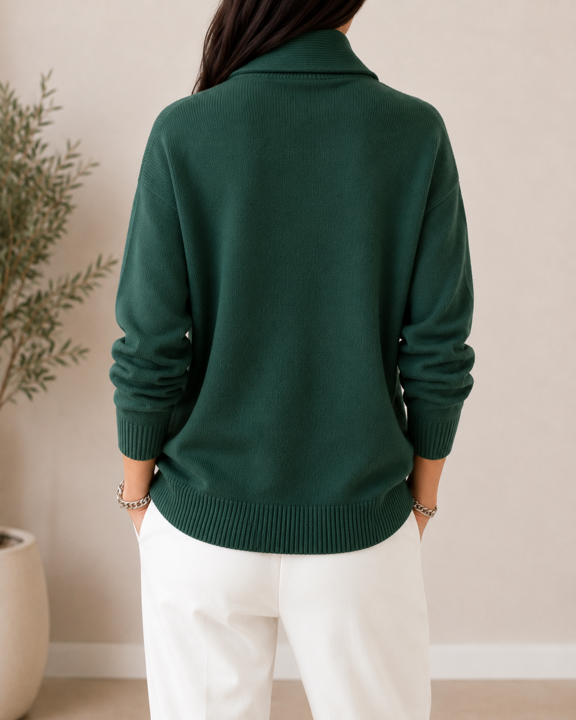 Back view of the dark green sweater showing its plain back, long sleeves, and ribbed hem and cuffs.