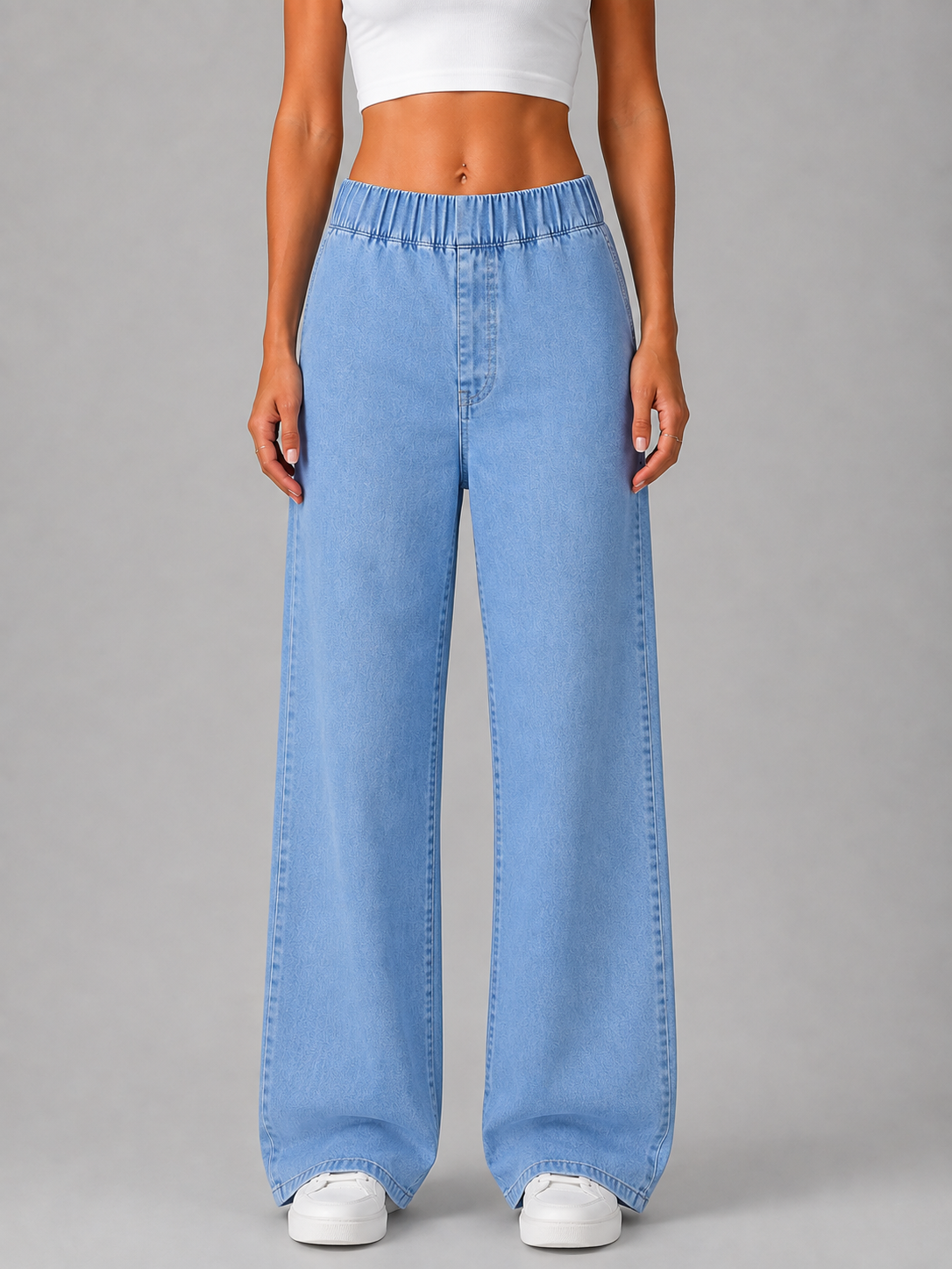 Front view of light blue wide-leg pull-on jeans with an elasticated high waist and full-length legs, styled with white trainers.