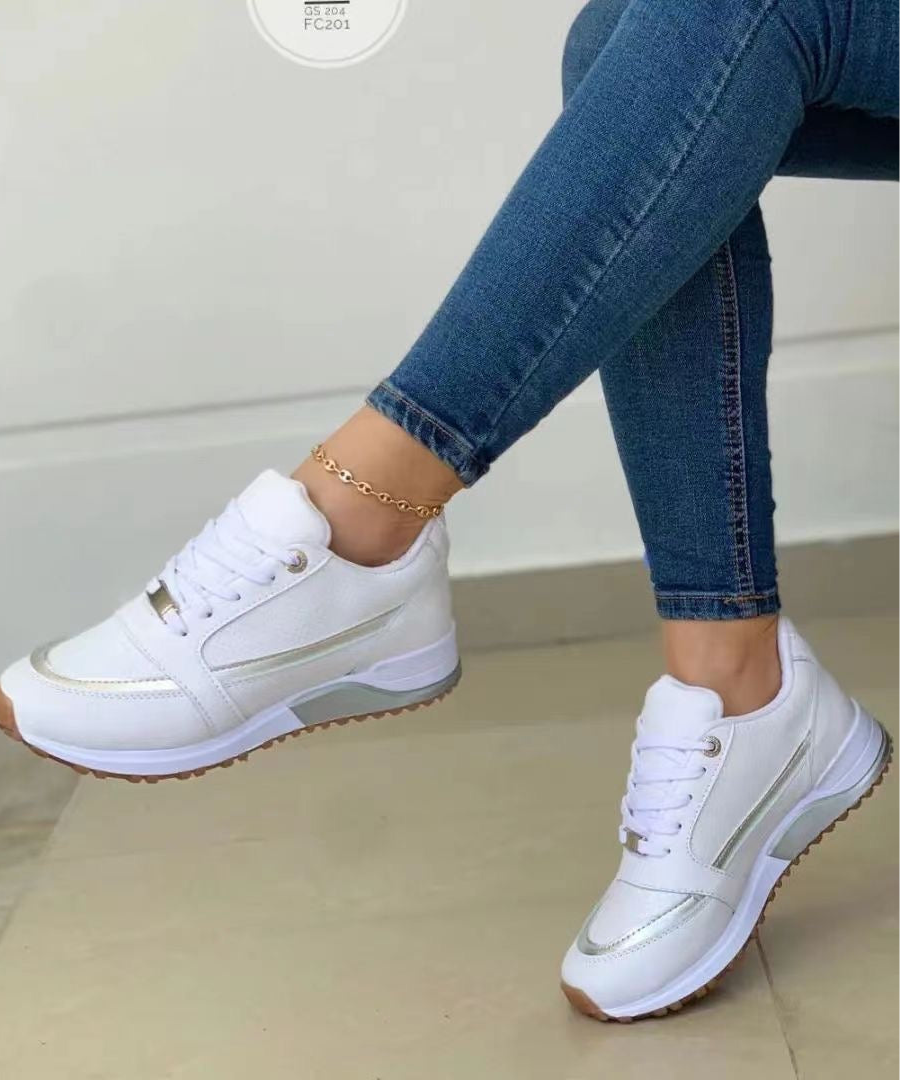 White low-top women's lace-up sneakers featuring subtle metallic side accents and a contrasting textured outsole.