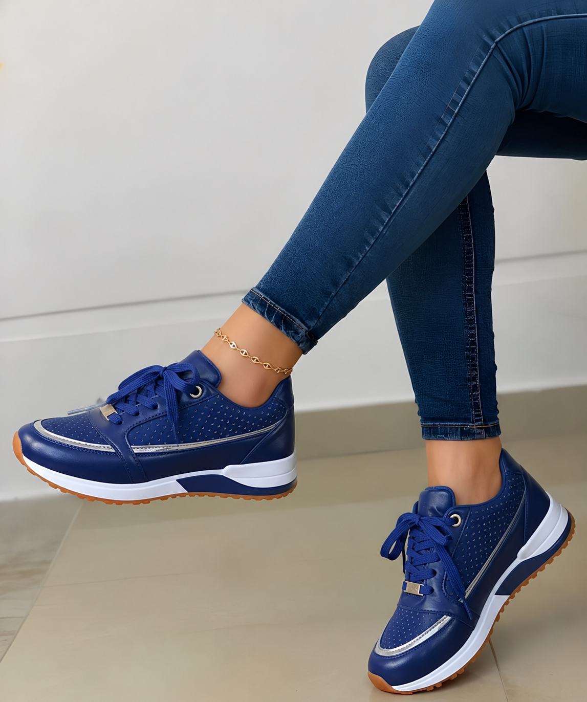 Navy blue low-top women's lace-up sneakers with perforated side panels, metallic detailing, and a brown-edged contrast sole.